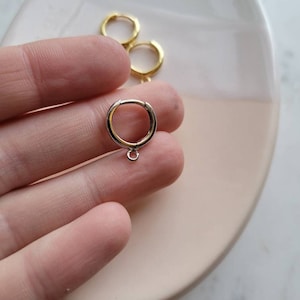 Puede incluir: Un par de pendientes de aro de oro con un peque&ntilde;o anillo de salto unido a uno de los aros.
