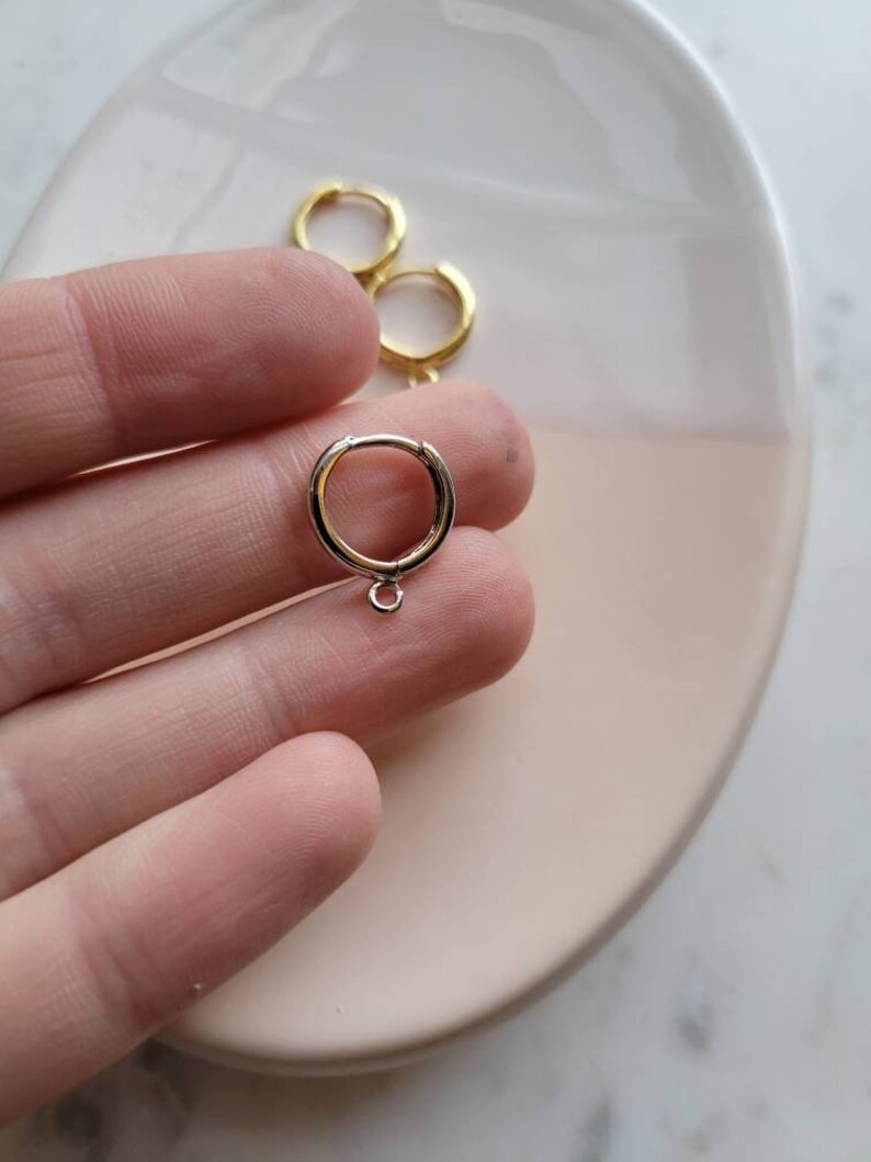 Puede incluir: Un par de pendientes de aro de oro con un peque&ntilde;o anillo de salto unido a uno de los aros.