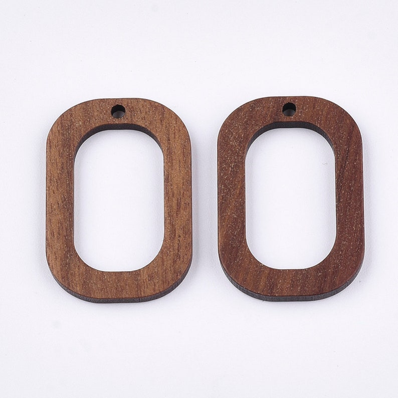 May include: Two unfinished wooden oval-shaped earring blanks with a hole at the top. The blanks are a light brown color.