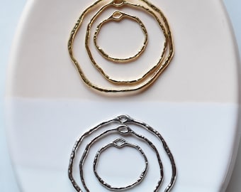 May include: Two sets of three gold and silver concentric circles with a textured finish. The circles are connected by a small loop at the top.
