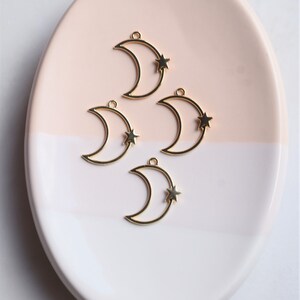 May include: Four gold-toned metal crescent moon charms with a small star attached to each moon.