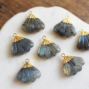 May include: Seven gold-toned metal charms with a fan-shaped design, each featuring a dark blue labradorite stone.