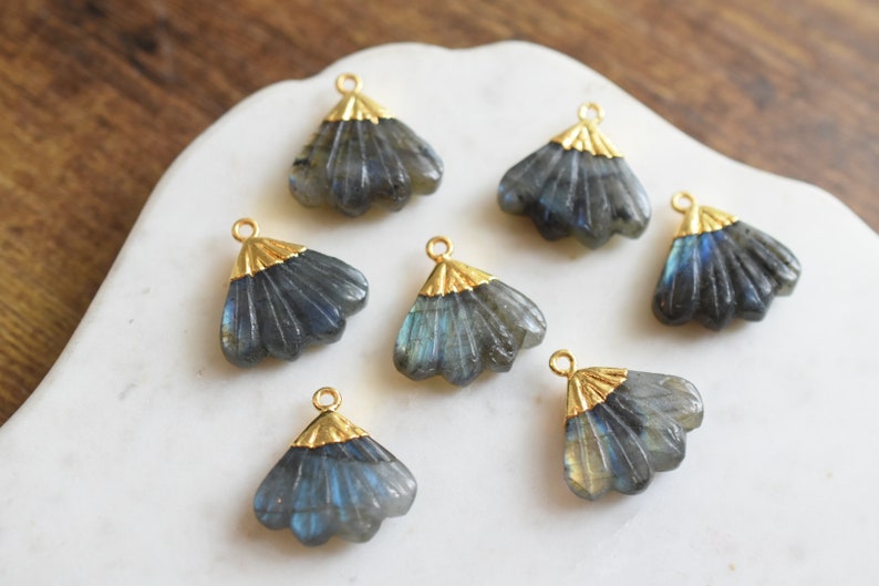 May include: Seven gold-toned metal charms with a fan-shaped design, each featuring a dark blue labradorite stone.