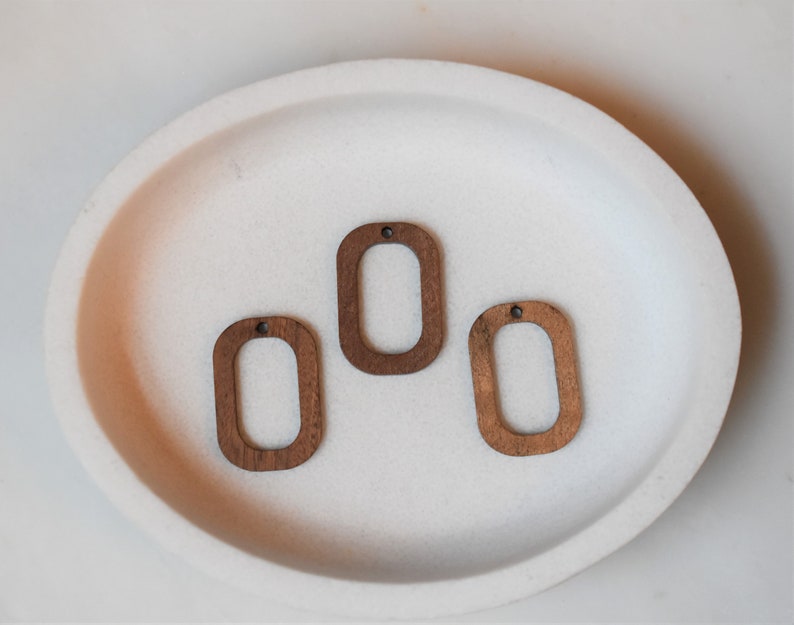 May include: Three unfinished wooden oval shapes with a hole in the top. The ovals are light brown and have a smooth surface.