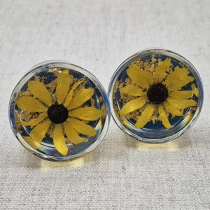 May include: A white ceramic mug with a black handle and the text "But First, Coffee" in a black, handwritten-style font. The mug is on a white surface.