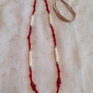 May include: A red and white beaded necklace with bone beads and a leather cord.