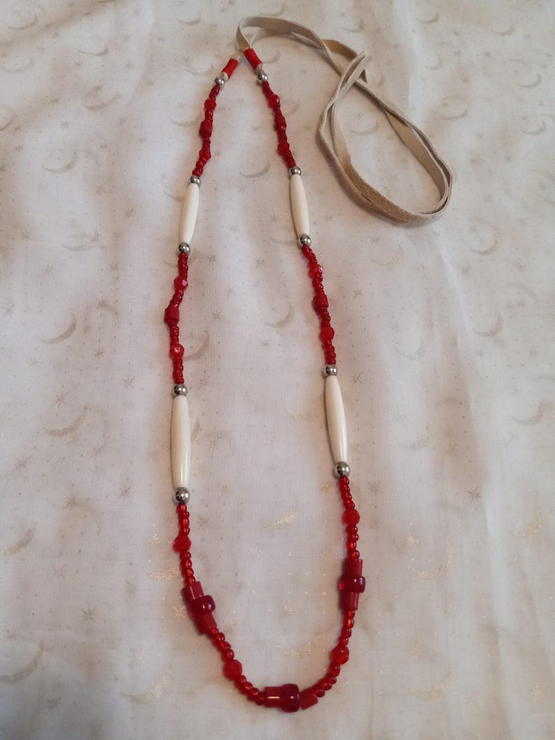 May include: A red and white beaded necklace with bone beads and a leather cord.