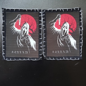 May include: Two square patches with a white Scream mask figure holding a knife against a red moon. The word "SCREAM" is printed in white. Each patch has a black border with white stitching.