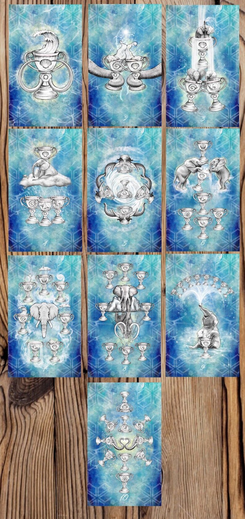 Puede incluir: Un juego de diez cartas de tarot con un fondo azul acuarela con copos de nieve blancos y un dise&ntilde;o de copa plateada. Cada carta presenta un n&uacute;mero diferente de copas y un elefante. Las cartas est&aacute;n numeradas del 1 al 10.
