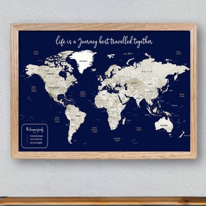 May include: A framed world map with a navy blue background and beige continents. The map is surrounded by a light wood frame. The text "Life is a journey best travelled together" is printed at the top of the map. The map is hanging on a white wall above a wooden dresser with black metal accents.