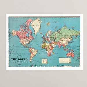 May include: A vintage world map print in a light blue, green, and pink colour scheme. The map is titled "Rand McNally & Co.'s New 11 x 14 World Map." The map is framed in a white frame and is hanging on a white wall.