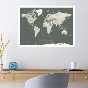 May include: A world map with a green background and beige countries. The map is framed and has the text "Our Family Travel Adventures" and "Steve, Jane, Mitchell & Sara" written below the map.