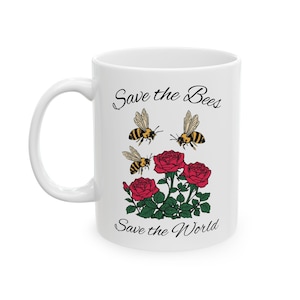 May include: White ceramic mug featuring the text "Save the Bees Save the World". The mug has a design of three bees and three red roses. The mug has a white handle and a white interior.