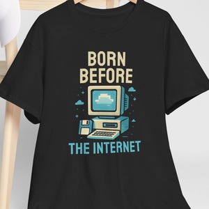 May include: Black t-shirt featuring a retro computer graphic with the text "BORN BEFORE THE INTERNET." The design includes a vintage computer monitor, a floppy disk, and a keyboard, all in a cartoon style.