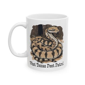 May include: White ceramic mug with a detailed illustration of a snake with brown and tan markings. The snake is coiled in front of a forest backdrop. The text "West Texas Pest Patrol" is printed below the snake.