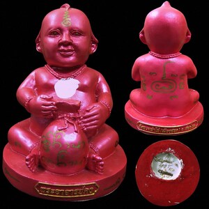 Op de afbeelding: Rood beeldje van een zittende, lachende figuur met een tas. De figuur heeft een rond hoofd en is versierd met gouden accenten. De basis heeft gouden tekst. Extra weergaven tonen de achterkant en de onderkant.