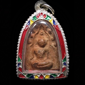 May include: A pendant with a seated Buddha figure within a clear, arched frame. The frame is edged with silver-coloured metal and a colourful enamel design of red, green, blue, and yellow. The pendant has a silver loop at the top.