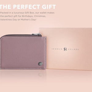 May include: A mauve leather wallet with a zipper closure and a silver logo. The wallet is in a gift box with the text "SERMAN BRANDS" on the top.