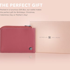 May include: A dusty rose-colored wallet with a zipper closure and white stitching, next to a matching gift box. The wallet has a small metal emblem. The text "SERMAN BRANDS" is on the gift box.