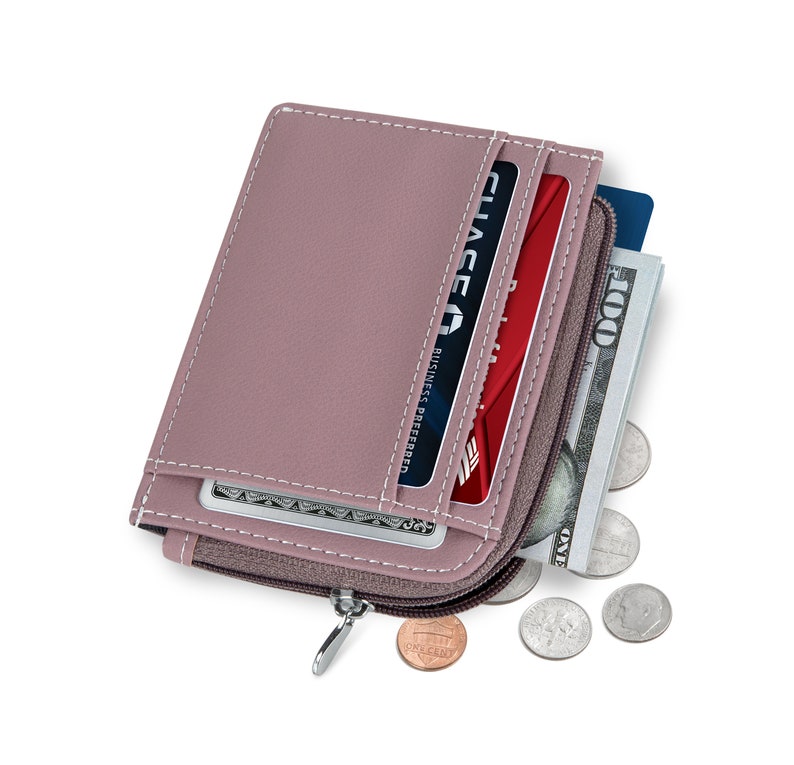May include: A small, zippered wallet made of light pink leather with a zipper closure. The wallet is open and shows a red credit card with the text "CHASE BUSINESS PREFERRED" and a few coins.