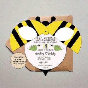 May include: A yellow and black bee-shaped invitation with a white circle in the centre. The text on the invitation reads "Lyla's Birthday! Our little honey bee is turning one. Join us to celebrate Sunday, 15th July at Buzz Avenue, Bumble Village from 1-3pm. RSVP to the Queen Bee 07917885267."