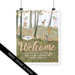 May include: A welcome sign for a baby shower with a woodland theme. The sign features a pink and green color scheme with a whimsical illustration of teddy bears having a picnic in the woods. The text on the sign reads "Welcome, A little bear is on the way! Join us to celebrate here today!"