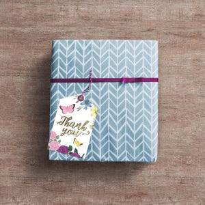 May include: A blue and white gift box with a chevron pattern. A white gift tag with a floral design and butterflies is attached to the box with a purple ribbon. The tag says "Thank you" in gold lettering.