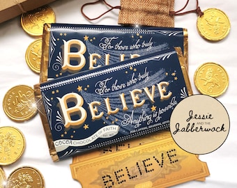 May include: Two chocolate bars with the words "For those who truly believe" and "Believe" printed on them. The bars are wrapped in blue and gold foil and have a gold star design. The bars are sitting on a white surface with gold coins and a brown paper bag.