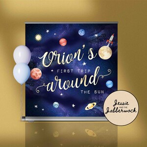 May include: A blue and purple space-themed backdrop with planets, stars, and a rocket ship. The text "Orion's First Trip Around The Sun" is written in gold script. A white circle with the text "Jessie and the Jabberwock" is in the bottom right corner.