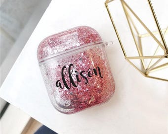 May include: Clear plastic case with pink glitter and the name "allison" printed in black. The case is designed to hold wireless earbuds.