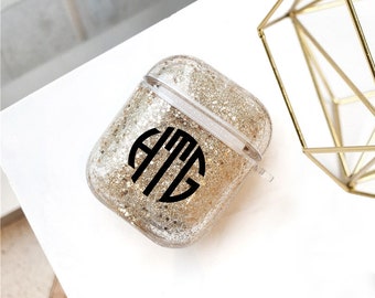 May include: A clear Airpods case with gold glitter and a black monogram "ATG" on the front.