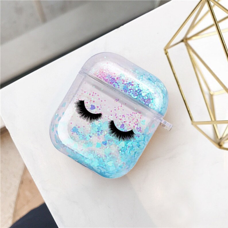 May include: Clear plastic case for AirPods with a blue and pink glitter design and black eyelashes printed on the front.
