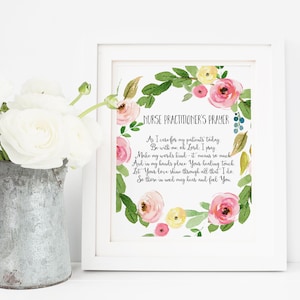 May include: A framed print featuring the "Nurse Practitioner's Prayer" in elegant script, surrounded by a watercolor floral wreath of pink, yellow, and green. A galvanized metal pitcher holds white flowers, adding a touch of rustic charm.