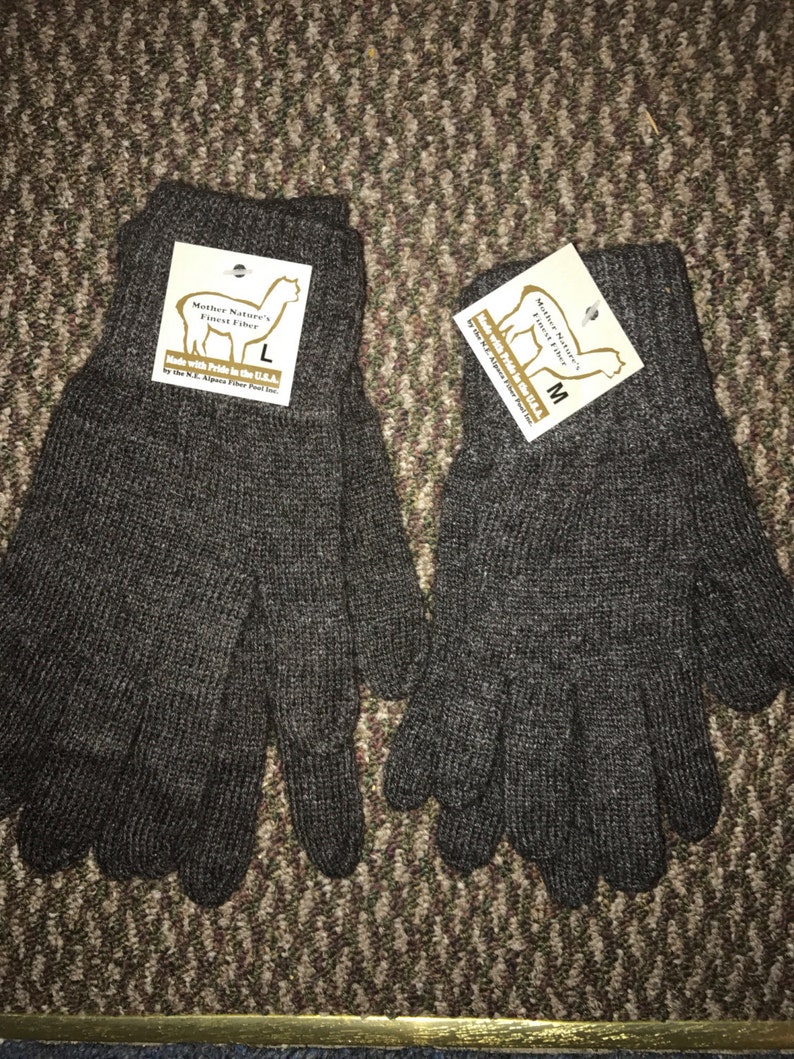 May include: A pair of brown alpaca wool gloves with a tag that reads "Mother Nature's Finest Fiber" and "Made with Pride in the USA". The tag also includes the size, either "L" or "M".