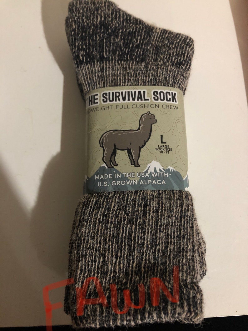 May include: A pair of black and gray alpaca wool socks with a full cushion crew design. The socks are labeled "The Survival Sock" and are made in the USA with U.S. grown alpaca. The label also states "Large Sock Size 10-13".