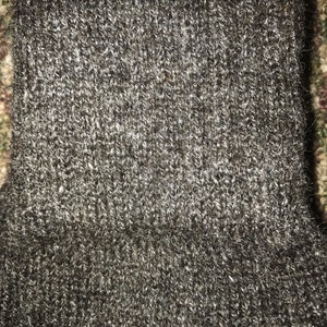 May include: Close-up of a dark gray knitted fabric with a fuzzy texture.