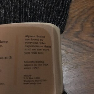 May include: A white label with black text that reads "Alpaca Socks are loved by everyone who experiences them and we are sure you will too!"  Manufacturing Alpaca in the USA since 1997. NEAFP P.O. Box 1306 Westport, MA 02790 www.neafp.com