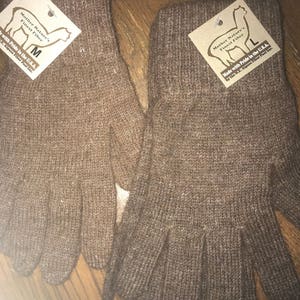 May include: A pair of brown alpaca wool gloves. The gloves are made in the USA and are labeled with the size "M" and "L".