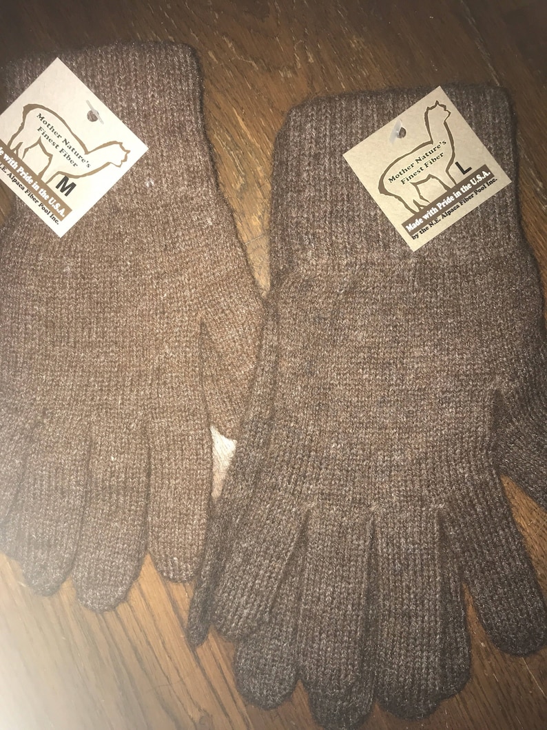 May include: A pair of brown alpaca wool gloves. The gloves are made in the USA and are labeled with the size "M" and "L".