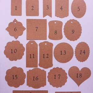 May include: Twenty brown paper gift tags with different shapes and sizes. The tags are numbered 1 through 20.
