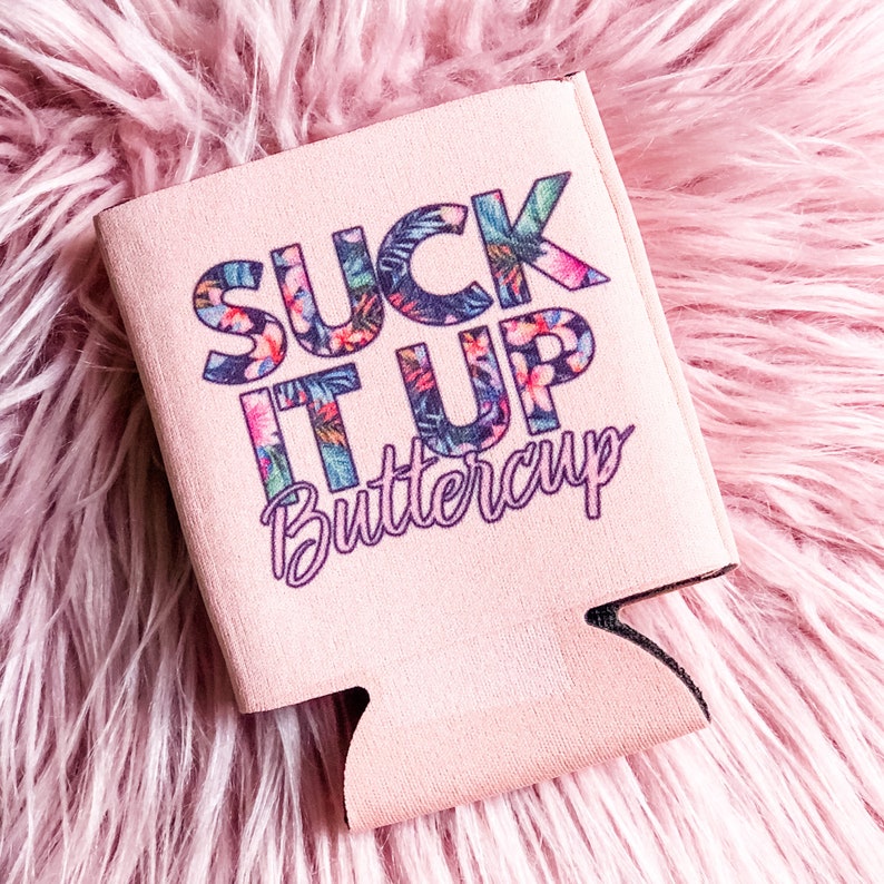 May include: A light pink can cooler with the phrase "SUCK IT UP Buttercup" in a tropical floral design. The cooler is made of a soft, insulating material and is designed to keep beverages cold.