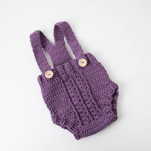 Puede incluir: Pantalones de bebé de punto de ganchillo morado con botones de madera.