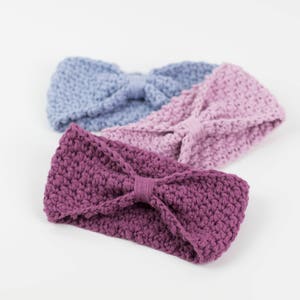 Könnte beinhalten: Drei gehäkelte Stirnbänder in verschiedenen Farben: lila, rosa und hellblau. Jedes Stirnband hat eine Schleife in der Mitte.