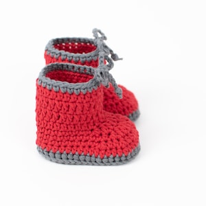 Op de afbeelding: Rode gehaakte babyschoentjes met grijze afwerking en strikjes.