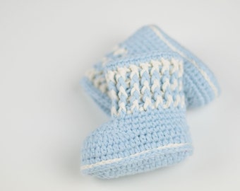 Könnte beinhalten: Ein Paar Babyschuhe in hellblau mit weißer Häkelborte. Die Schuhe sind aus einem weichen, strukturierten Garn gefertigt.