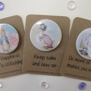 May include: Three brown card stock tags with white text and a round button featuring a different character from Beatrix Potter's children's books. The first tag reads "Happiness is stitching". The second tag reads "Keep calm and sew on". The third tag reads "Do more of what makes you happy".