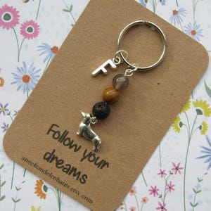 May include: A silver dachshund charm keyring with an 'F' charm and decorative beads. The keyring is attached to a brown card with the text "Follow your dreams" and the Etsy shop's URL.