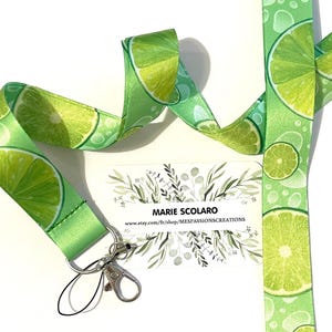 Puede incluir: Un cordón verde con un patrón de lima y un llavero plateado. El cordón tiene el texto "MARIE SCOLARO" y "www.etsy.com/fr/shop/MESSPASSIONSCREATIONS" impreso en él.