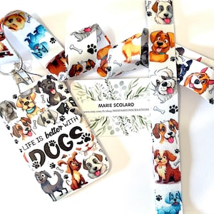 May include: A collection of dog-themed accessories, including a lanyard, badge holder, and fabric strips. The items feature colorful illustrations of various dog breeds, paw prints, and bones on a white background. The badge holder reads "Life is better with Dogs."