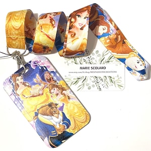 Può includere: Un cordino e un porta badge con personaggi de La Bella e la Bestia. Il cordino è giallo e presenta immagini di Belle e la Bestia. Il porta badge ha un'immagine colorata di Belle, la Bestia e altri personaggi del film.